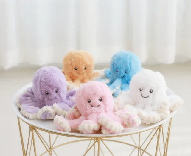 Peluches pieuvres colorées douces rose, bleu, violet, blanc et beige sur table ronde