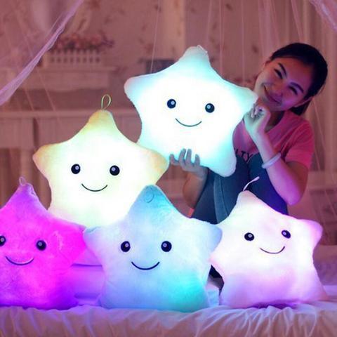 Femme souriante avec des coussins lumineux en forme d'étoiles souriantes de différentes couleurs dans une chambre